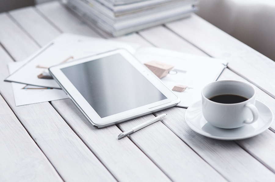 Kaffeetasse, Tablet und Pläne auf einem Schreibtisch